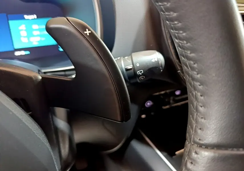Gros plan sur la palette de changement de vitesses droite en plastique noir et volant cuir du Citroën C5 Aircross hybride 2022.
