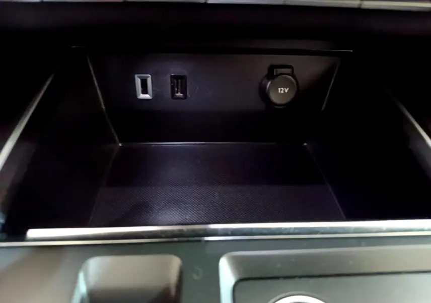 Gros plan sur la prise 12V et ports USB dans le rangement central noir du Citroën C5 Aircross hybride rechargeable 2022.