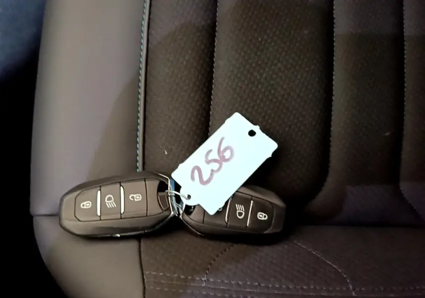 Gros plan sur deux clés noires avec étiquette posées sur un siège en tissu noir du Citroën C5 Aircross hybride rechargeable.