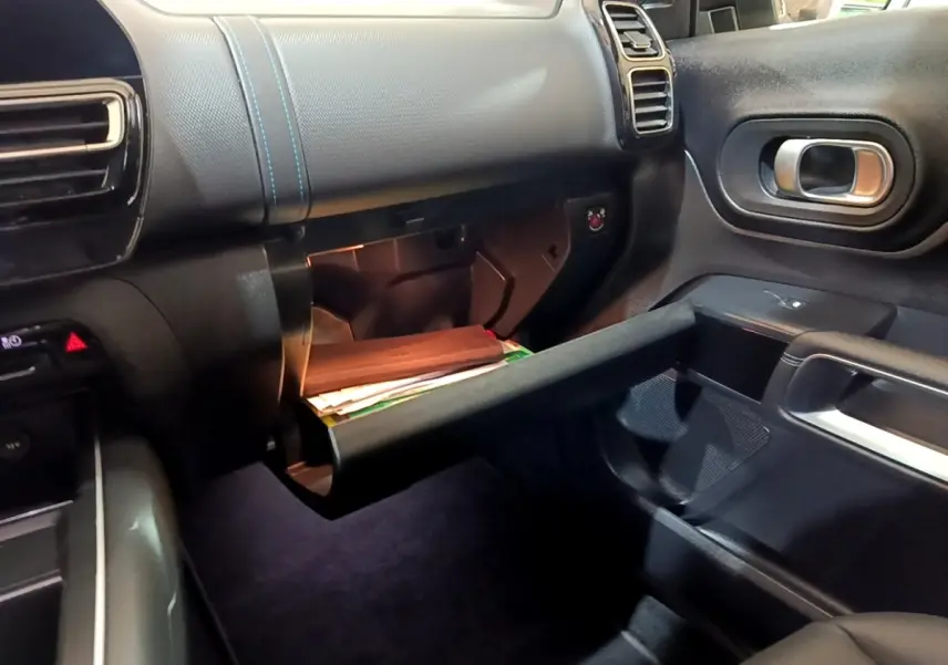 Intérieur noir du Citroën C5 Aircross hybride rechargeable 2022, vue côté passager avec boîte à gants ouverte et éclairage intérieur.