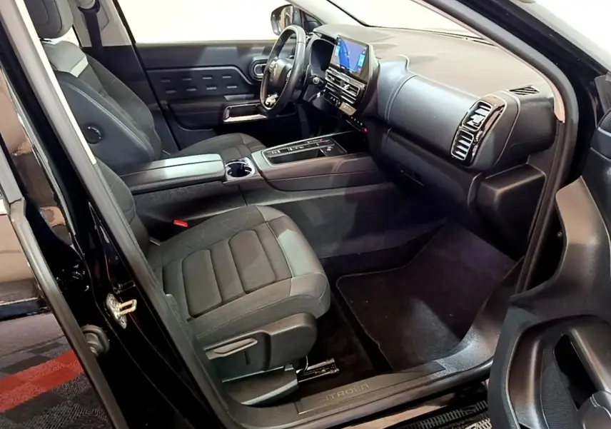 Vue intérieure côté conducteur du Citroën C5 Aircross hybride noir, mettant en valeur le tableau de bord et les sièges avant.