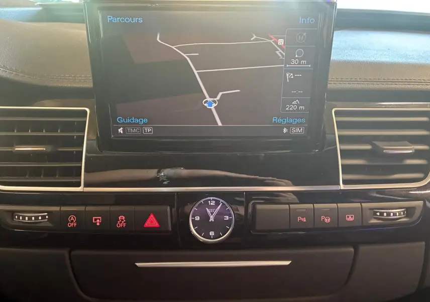 Vue rapprochée du tableau de bord noir de l'Audi A8 2016 avec écran GPS et horloge analogique centrale.