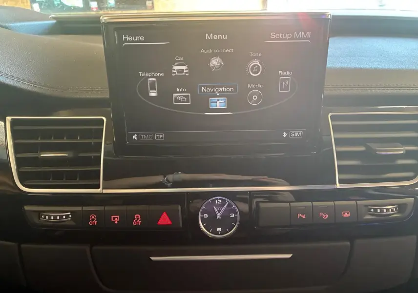 Vue intérieure centrée sur l’écran de navigation et la console noire de l’Audi A8 3.0 TDI 2016 avec horloge analogique.