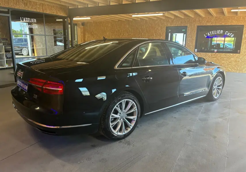 Audi A8 3.0 TDI noir vue 3/4 arrière droit dans un garage avec jantes alliage et finition chrome.