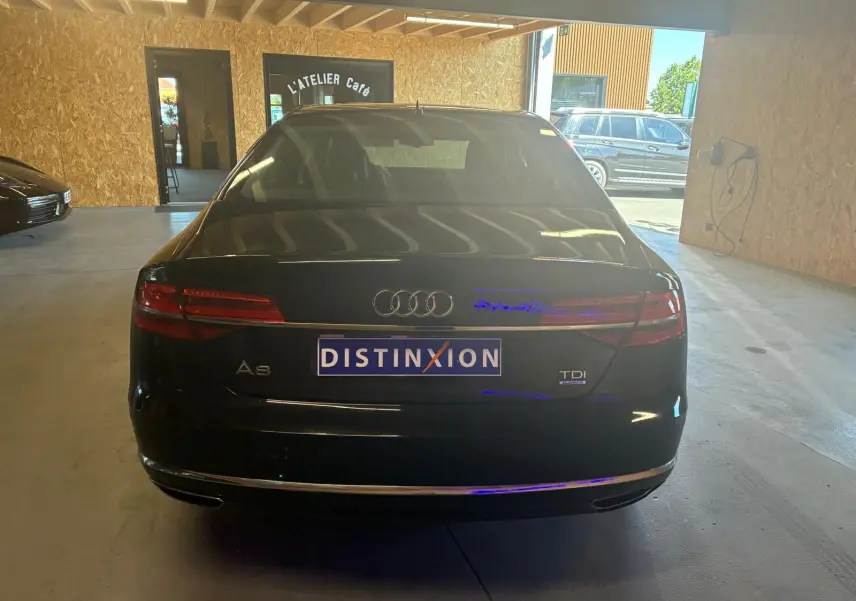 Vue arrière d'une Audi A8 noire 2016 avec logo TDI et plaque Distinxion dans un garage.