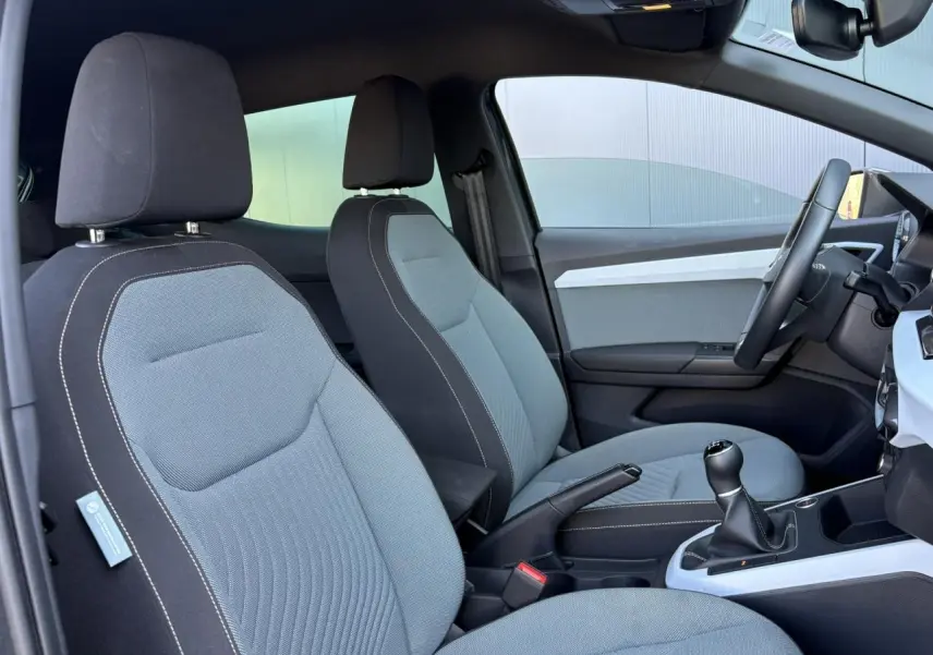 Vue intérieure côté droit montrant les sièges gris clair avec surpiqûres blanches et la console centrale d'une SEAT Ibiza 2025.