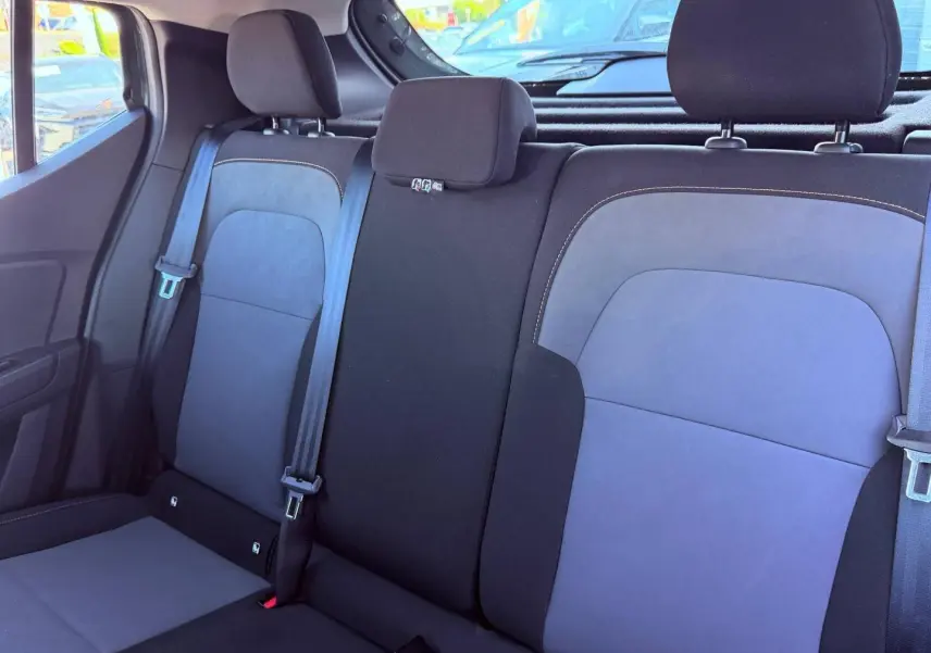 Vue intérieure sur la banquette arrière en tissu brun cuivré de la Dacia Sandero 2025, avec appuie-têtes et ceintures visibles.