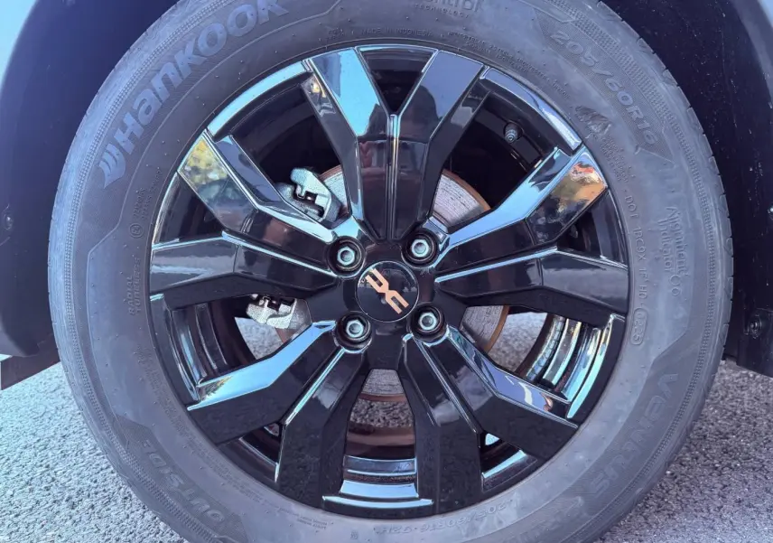 Gros plan sur la jante noire brillante de la Dacia Sandero 1.0 ECO-G 100ch Stepway Extreme, avec logo central cuivré.