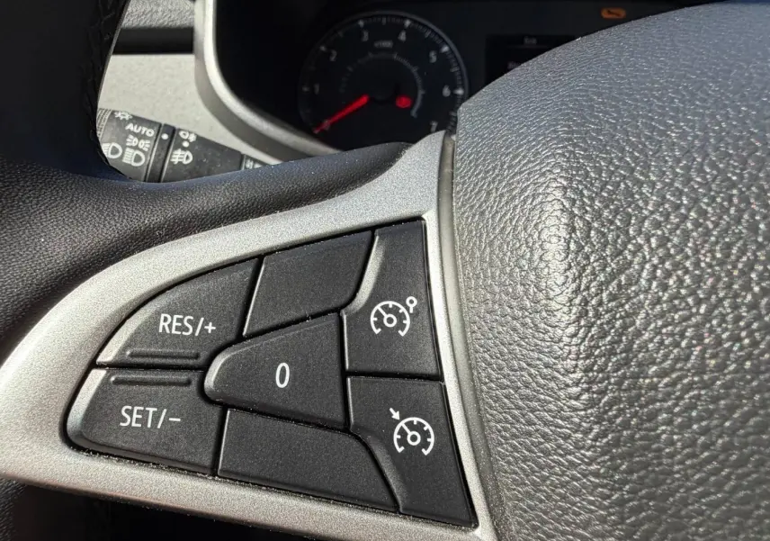 Gros plan sur les commandes du régulateur de vitesse au volant d’une Dacia Sandero 2025, intérieur noir.