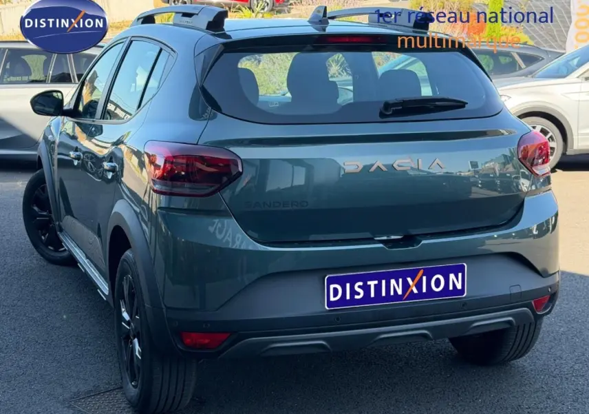 Vue 3/4 arrière d'une Dacia Sandero Stepway 2025 vert cèdre métallisé avec jantes noires et barres de toit.