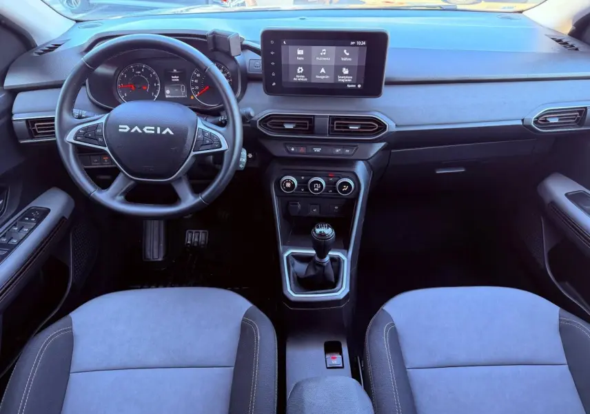 Vue intérieure avant du tableau de bord et volant de la Dacia Sandero 2025 avec écran tactile et boîte manuelle.