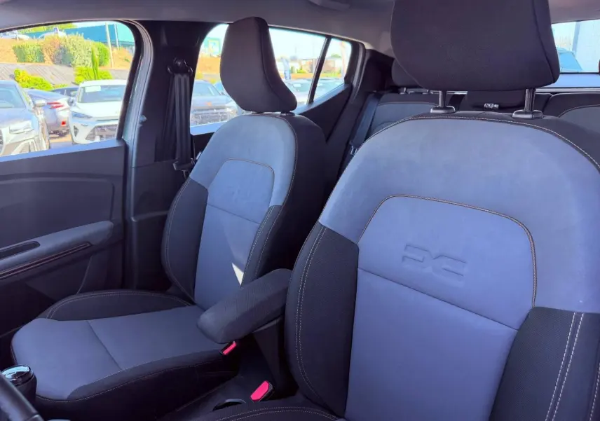 Vue intérieure des sièges avant de la Dacia Sandero Stepway Extreme avec tissu brun cuivré et accoudoir central.