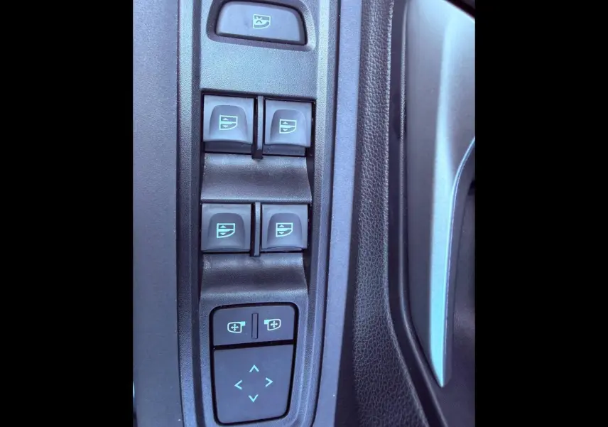 Gros plan sur les commandes des vitres électriques et réglages des rétroviseurs côté conducteur du Dacia Sandero 2025.