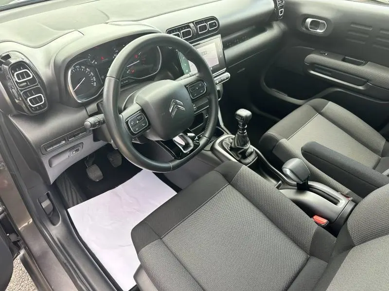 Vue intérieure côté conducteur du Citroën C3 Aircross 2021, avec volant cuir, tableau de bord noir et sièges gris.