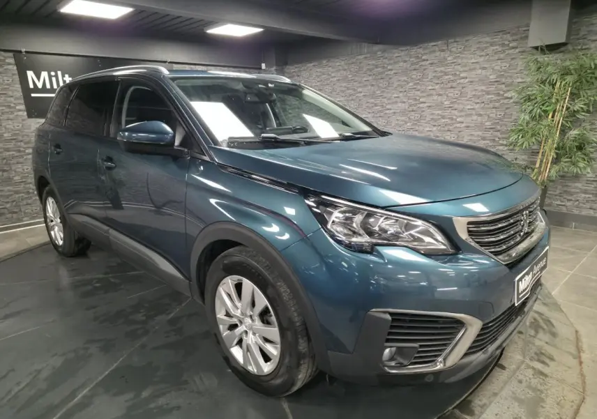 Peugeot 5008 bleu métallisé vue 3/4 avant droit avec calandre chromée et jantes alliage 17 pouces.