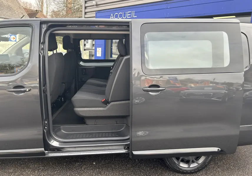 Vue latérale gauche d’un Citroën Jumpy cabine approfondie gris titane avec porte coulissante ouverte montrant les sièges arrière.