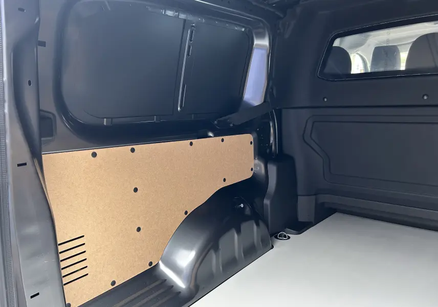 Vue intérieure arrière droite du Citroën Jumpy cabine approfondie gris titane, montrant l'espace de chargement et la cloison bois.