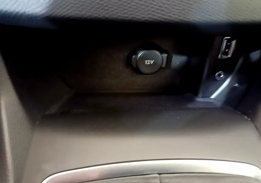 Prise 12V et port USB en gros plan dans l’espace de rangement central intérieur de la Peugeot 308 gris foncé.
