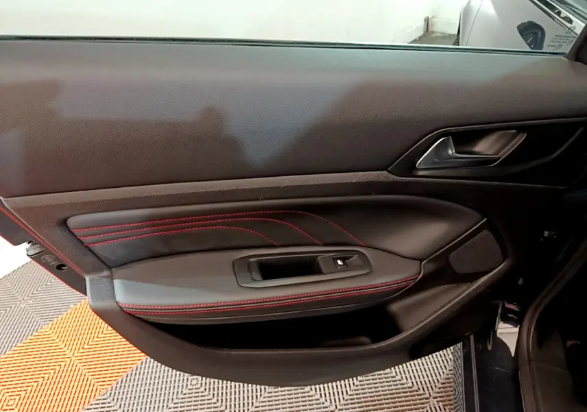 Vue rapprochée de la porte intérieure côté gauche d'une Peugeot 308 GT Line avec surpiqûres rouges et poignée noire.