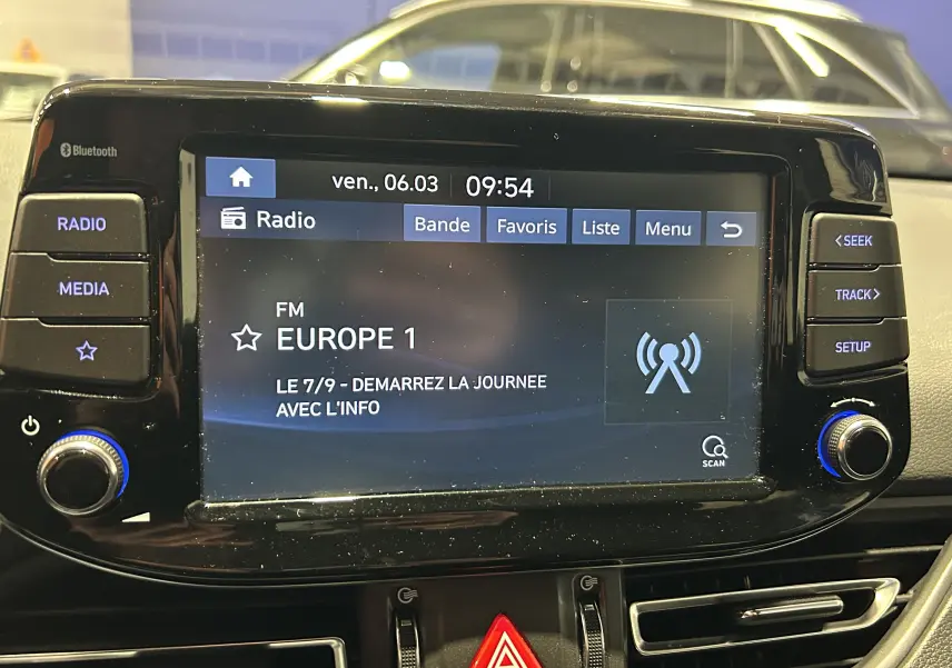 Vue rapprochée de l’écran multimédia de la Hyundai i30 SW 2022, affichant la radio FM Europe 1, avec commandes tactiles et boutons autour.