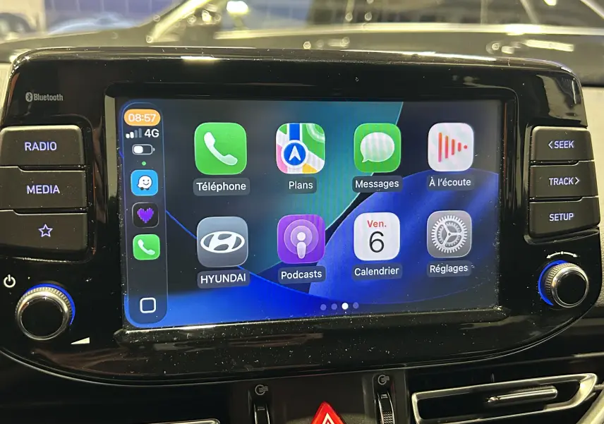 Écran tactile central de la Hyundai i30 SW 2022 affichant les applications Apple CarPlay, entouré de commandes noires brillantes.