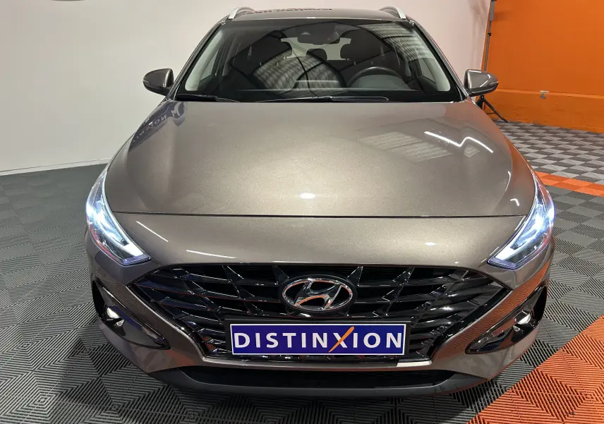 Vue avant rapprochée d’une Hyundai i30 SW 2022 en couleur bronze métallique avec phares LED allumés et calandre noire brillante.