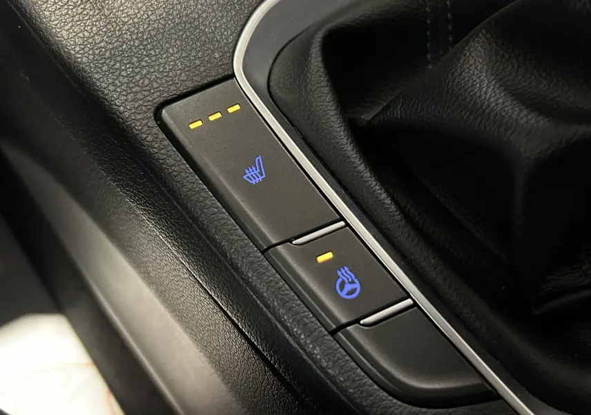 Gros plan sur les boutons de sièges et volant chauffants dans l’habitacle noir de la Hyundai i30 SW 2022.