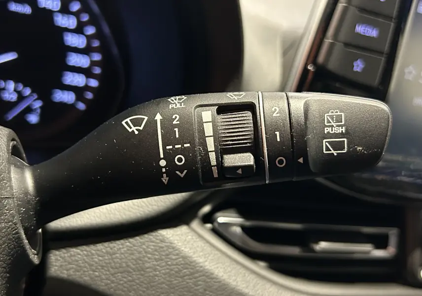 Gros plan sur la commande d’essuie-glace à droite du volant dans l’habitacle gris foncé de la Hyundai i30 SW 2022.