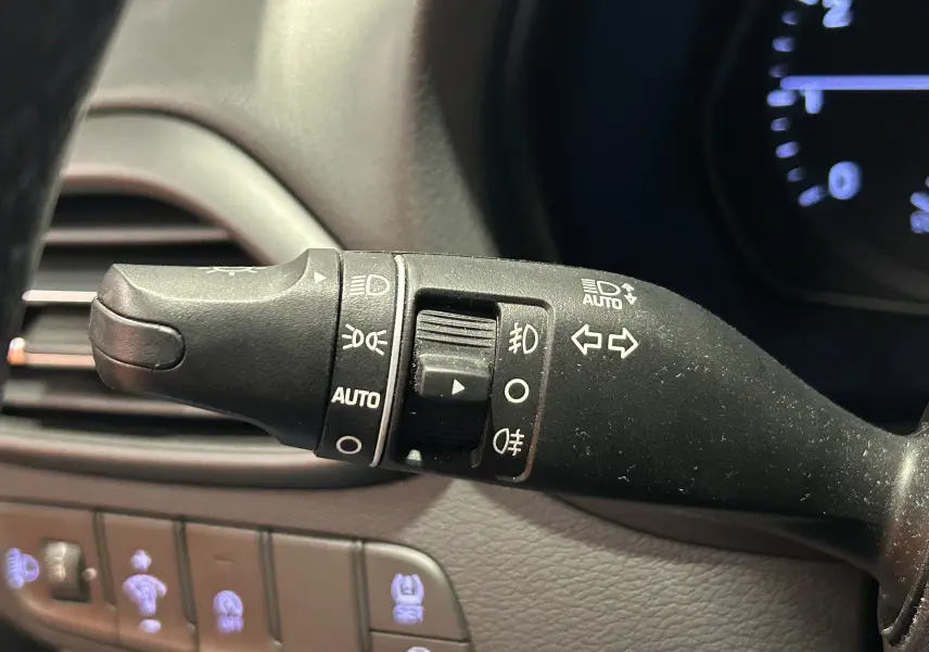 Gros plan sur la commande des phares et clignotants dans l’habitacle gris foncé de la Hyundai i30 SW 2022.