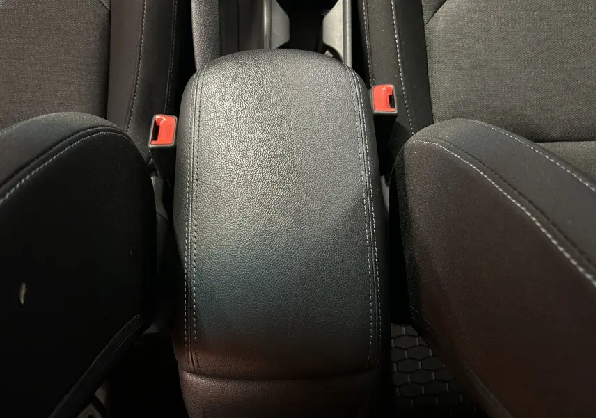 Gros plan sur l'accoudoir central en cuir noir et les sièges en tissu gris foncé de la Hyundai i30 SW 2022.