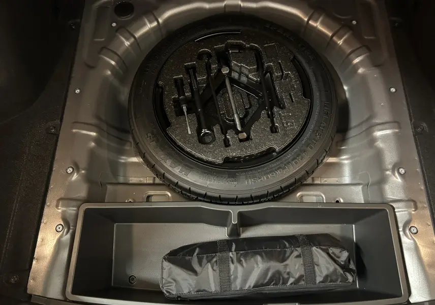 Vue plongeante sur la roue de secours et les outils de bord dans le coffre d'une Hyundai i30 SW Silky Bronze Metal.