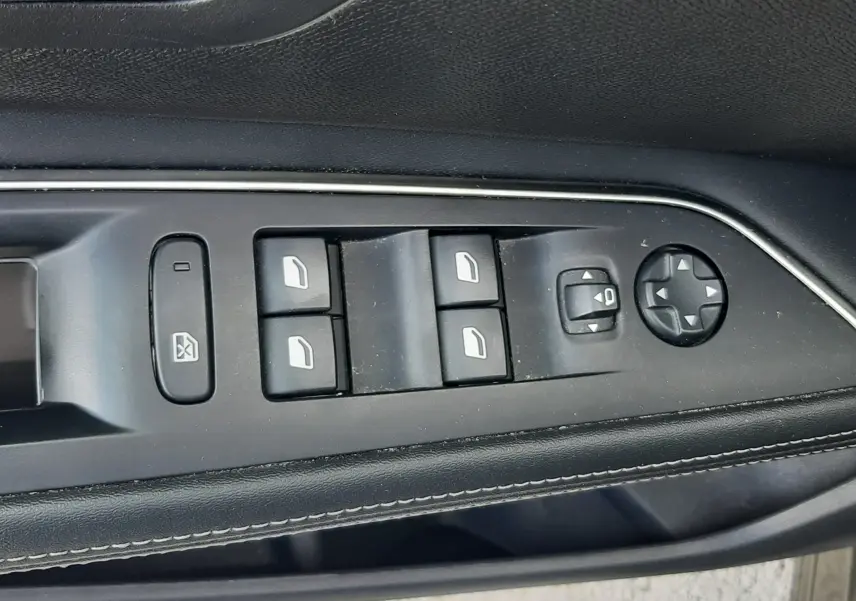 Vue rapprochée des commandes de lève-vitres et réglage des rétroviseurs côté conducteur du Peugeot 3008 gris Amazonite.