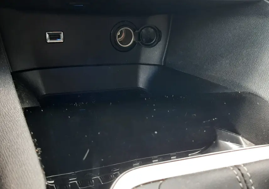 Gros plan sur la console centrale noire du Peugeot 3008 2019, montrant une prise USB et un allume-cigare ouverts.