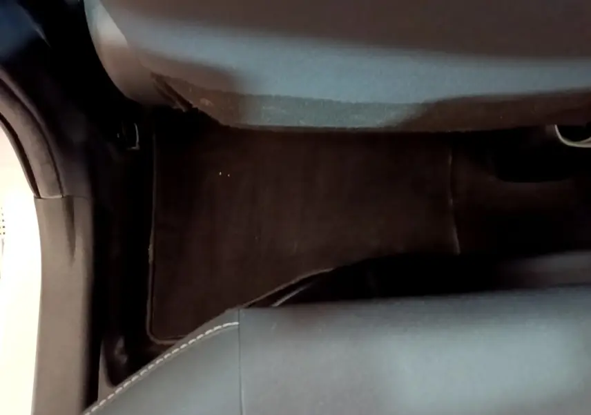 Vue rapprochée du plancher et de la base du siège avant droit d’une Toyota Yaris blanche, intérieur sombre.