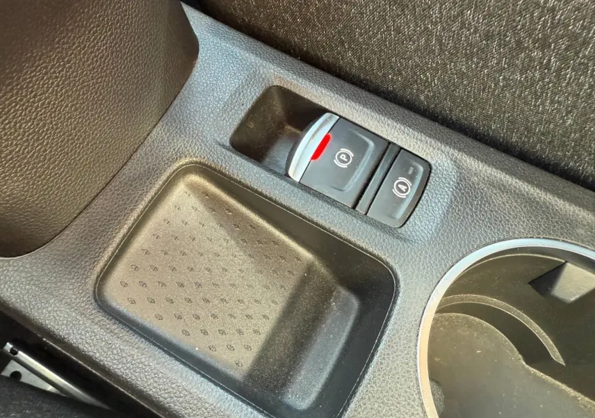 Gros plan sur la console centrale noire du Renault Captur 2025 avec frein à main électronique et rangement.