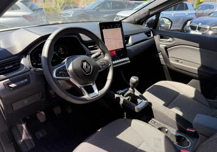 Vue intérieure côté conducteur du Renault Captur 2025, volant multifonction, écran tactile vertical et boîte manuelle.