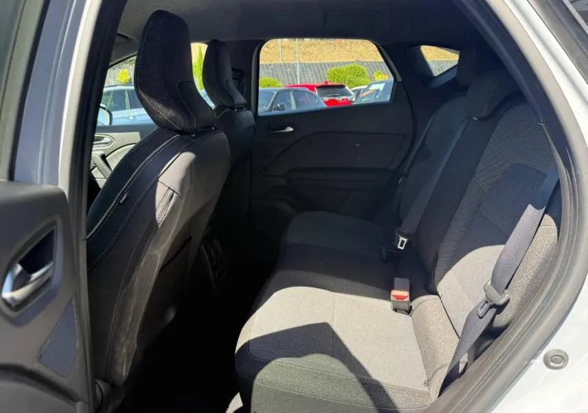 Vue intérieure côté arrière droit du Renault Captur 2025, sièges tissu gris et ceintures visibles.