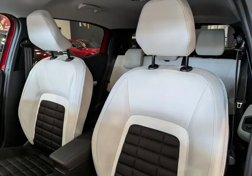 Vue rapprochée des sièges avant en cuir noir et blanc du Citroën C3 Aircross Hybride 2026 avec intérieur lumineux.
