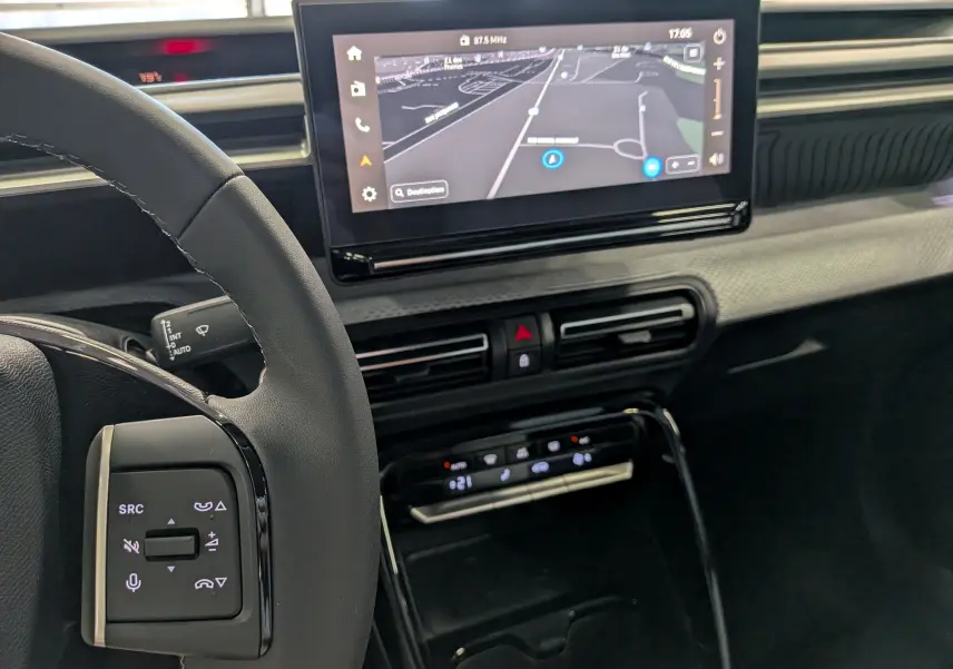 Vue intérieure du tableau de bord et volant du Citroën C3 Aircross hybride, avec écran tactile de navigation et commandes au volant.