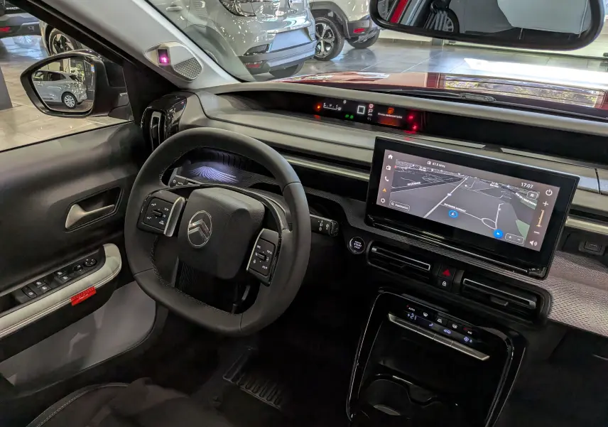 Vue intérieure côté conducteur du Citroën C3 Aircross hybride rouge Elixir, avec tableau de bord numérique et écran tactile central.