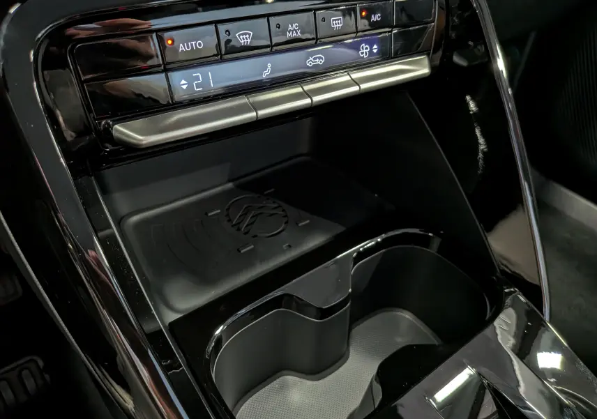 Gros plan sur la console centrale noire brillante de la Citroën C3 Aircross hybride 2026, avec commandes climatisation et porte-gobelets.