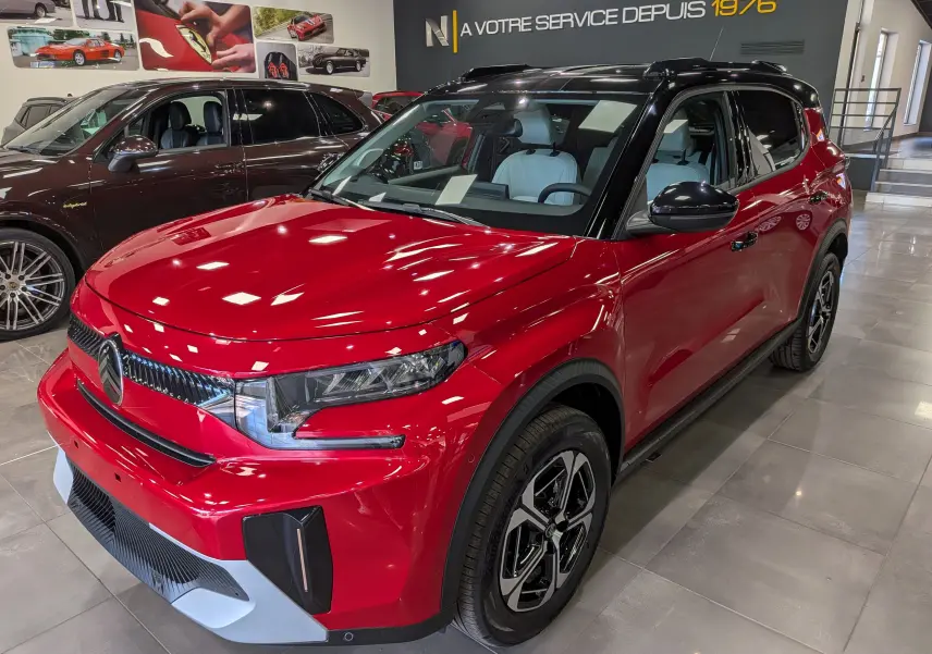 Citroën C3 Aircross hybride rouge Elixir avec toit noir, vue 3/4 avant droit en intérieur showroom.