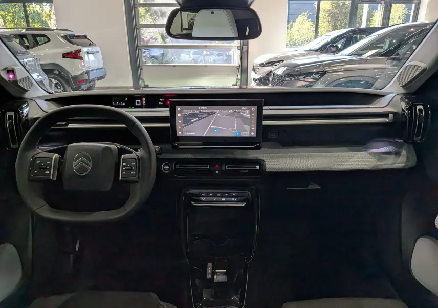 Vue intérieure frontale du tableau de bord de la Citroën C3 Aircross hybride 2026 avec écran tactile et volant multifonction.