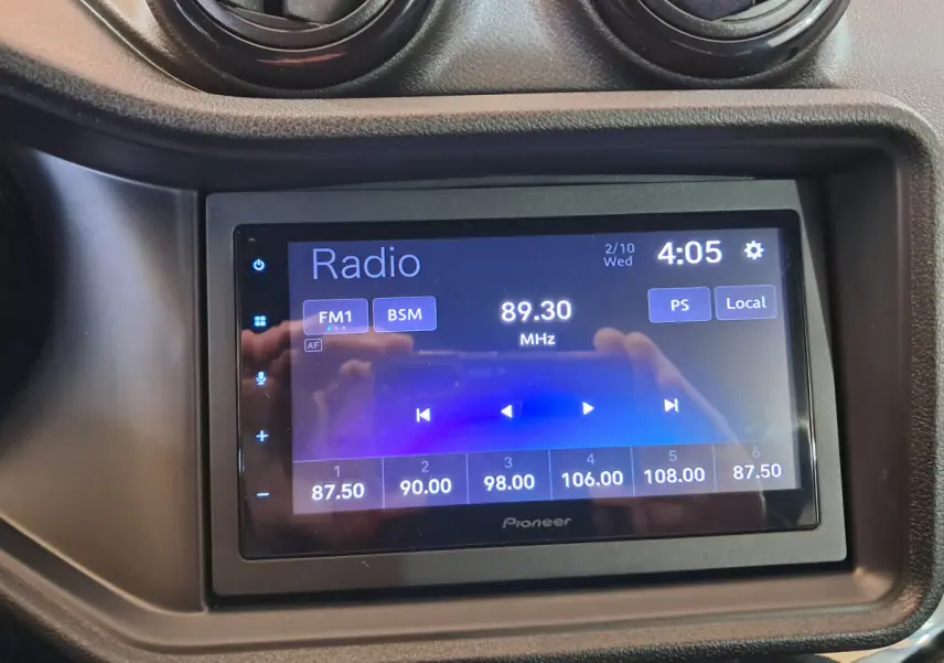 Écran tactile Pioneer de la radio FM affichant 89,30 MHz dans l'habitacle d'une Aixam Ambition rouge 2025.