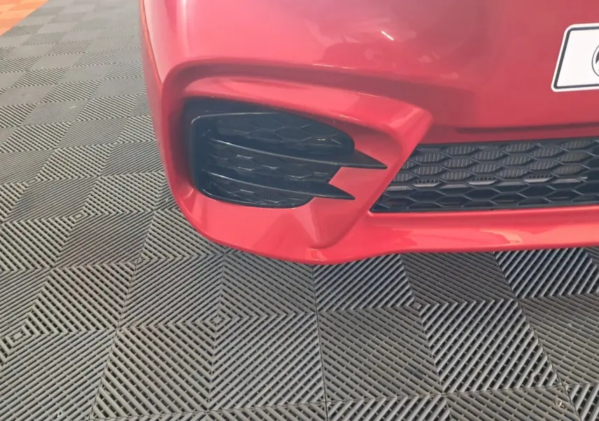 Gros plan sur l'entrée d'air avant gauche rouge de l'AIXAM AMBITION 2025 avec grille noire en nid d'abeille.