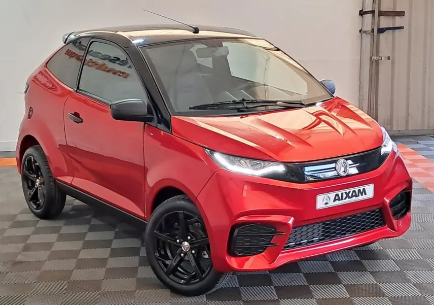 Vue 3/4 avant d'une Aixam Ambition rouge 2025 avec jantes noires et rétroviseur caméra côté gauche.
