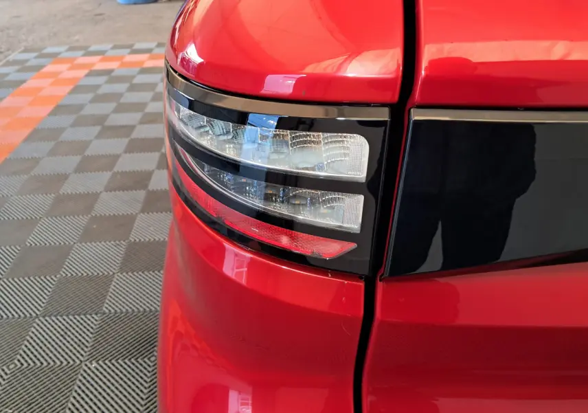 Gros plan sur le feu arrière droit rouge de l'AIXAM AMBITION 2025 avec détails noirs brillants et surface lisse.