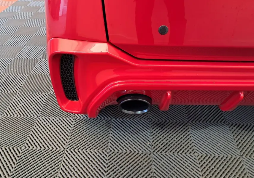 Gros plan sur l'arrière droit rouge de l'AIXAM AMBITION 2025, mettant en valeur la sortie d'échappement et le pare-chocs sport.
