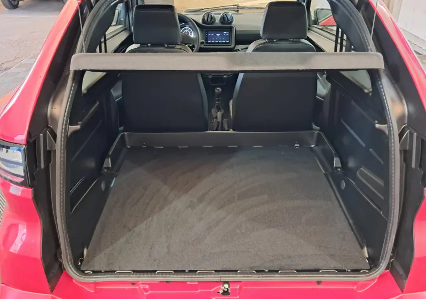 Vue arrière ouverte du coffre d'une Aixam Ambition rouge 2025, montrant l'intérieur spacieux et les sièges avant noirs.