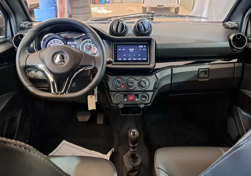 Vue intérieure frontale de l'AIXAM AMBITION rouge 2025, tableau de bord avec écran tactile et volant multifonction.